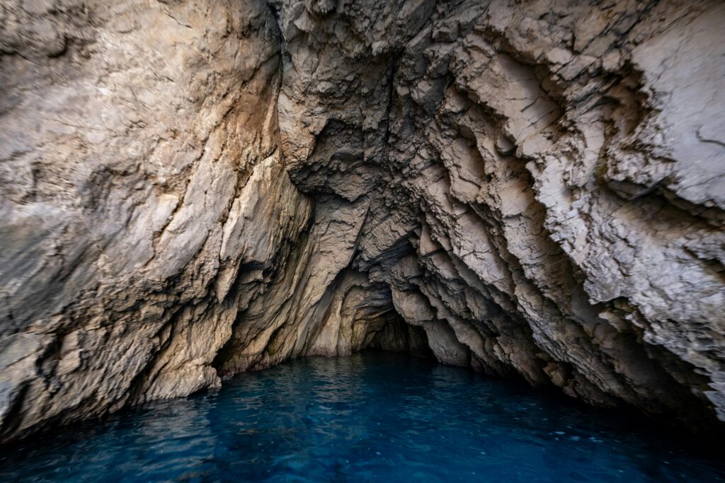 Explore a dramatic limestone cave with stunning blue water, capturing natural beauty and geological features.