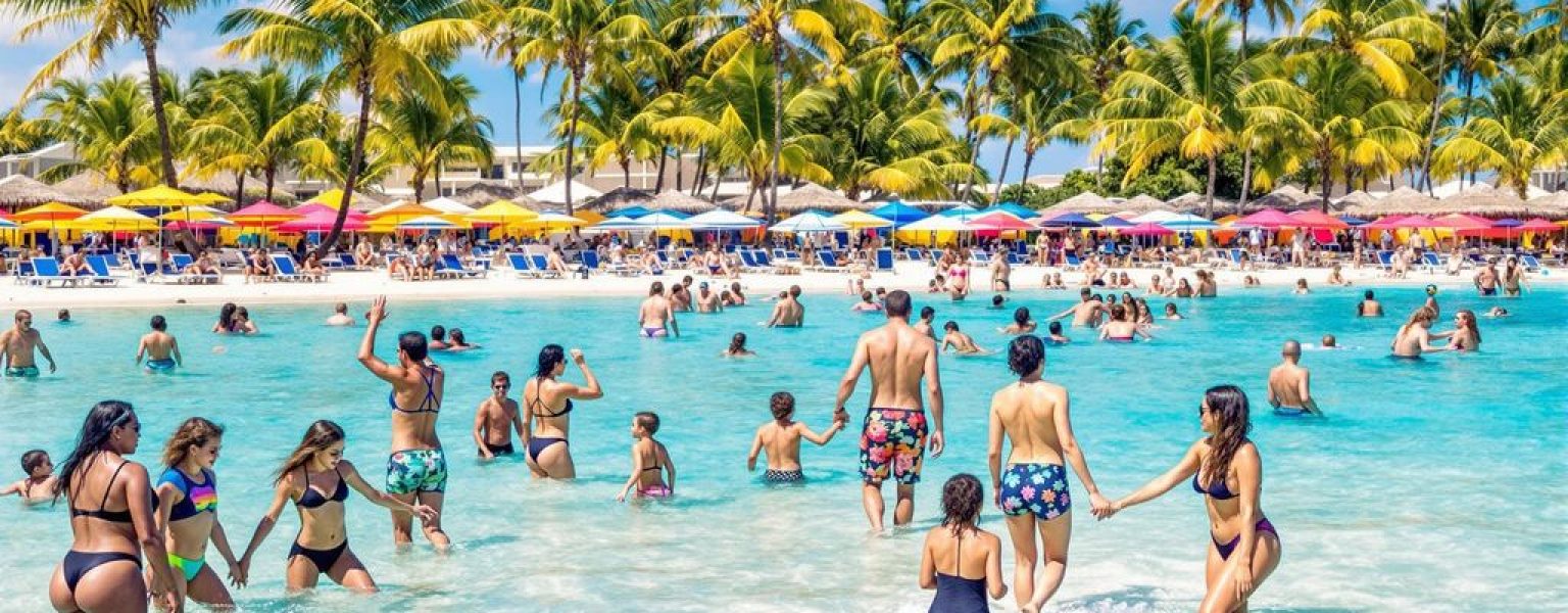 Families relaxing on a beautiful beach at a resort.
